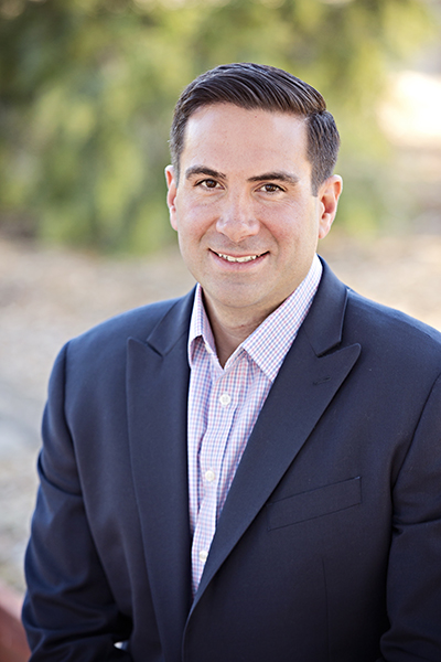 A man in a suit and tie smiling for the camera.